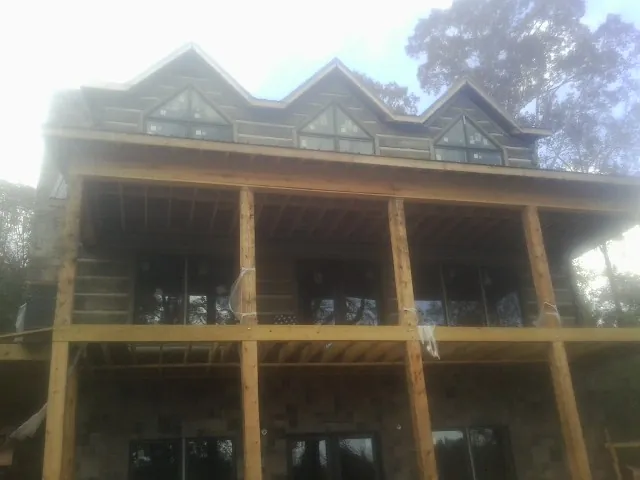 Dormers and porch framing on a large log home under construction — Roof Coating work by our crew in Ellenburg Center