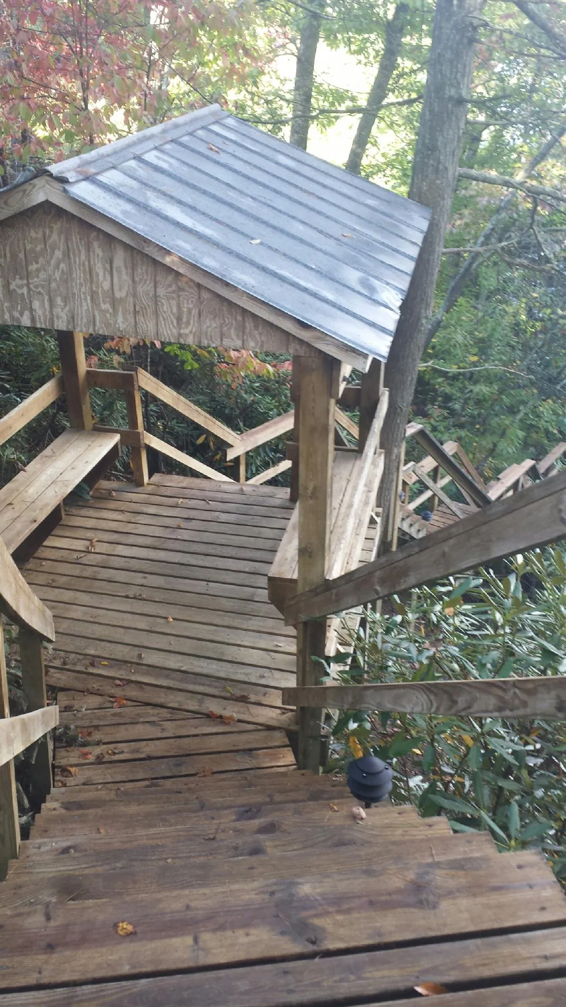 Metal roofed shelter over wooden steps on a wooded walkway — Skylight Repair & Installation work by our crew in Ellenburg Center